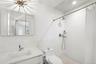 Full bath featuring a tile shower, vanity, tile walls, and wainscoting