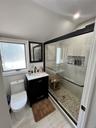 Walk-in shower with pebble tile flooring and glass enclosure