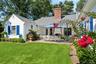 Back of house with a shingled roof, a patio, a chimney, and a lawn