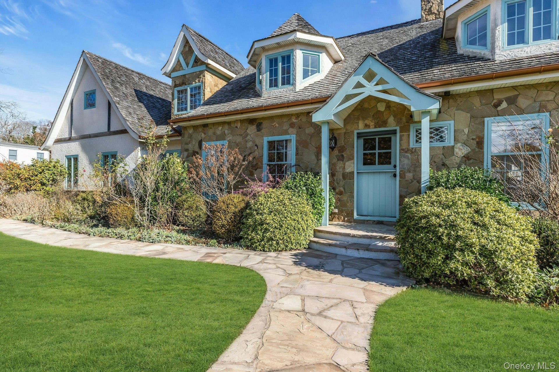 Property entrance with a lawn, a high end roof, stone siding, and a chimney