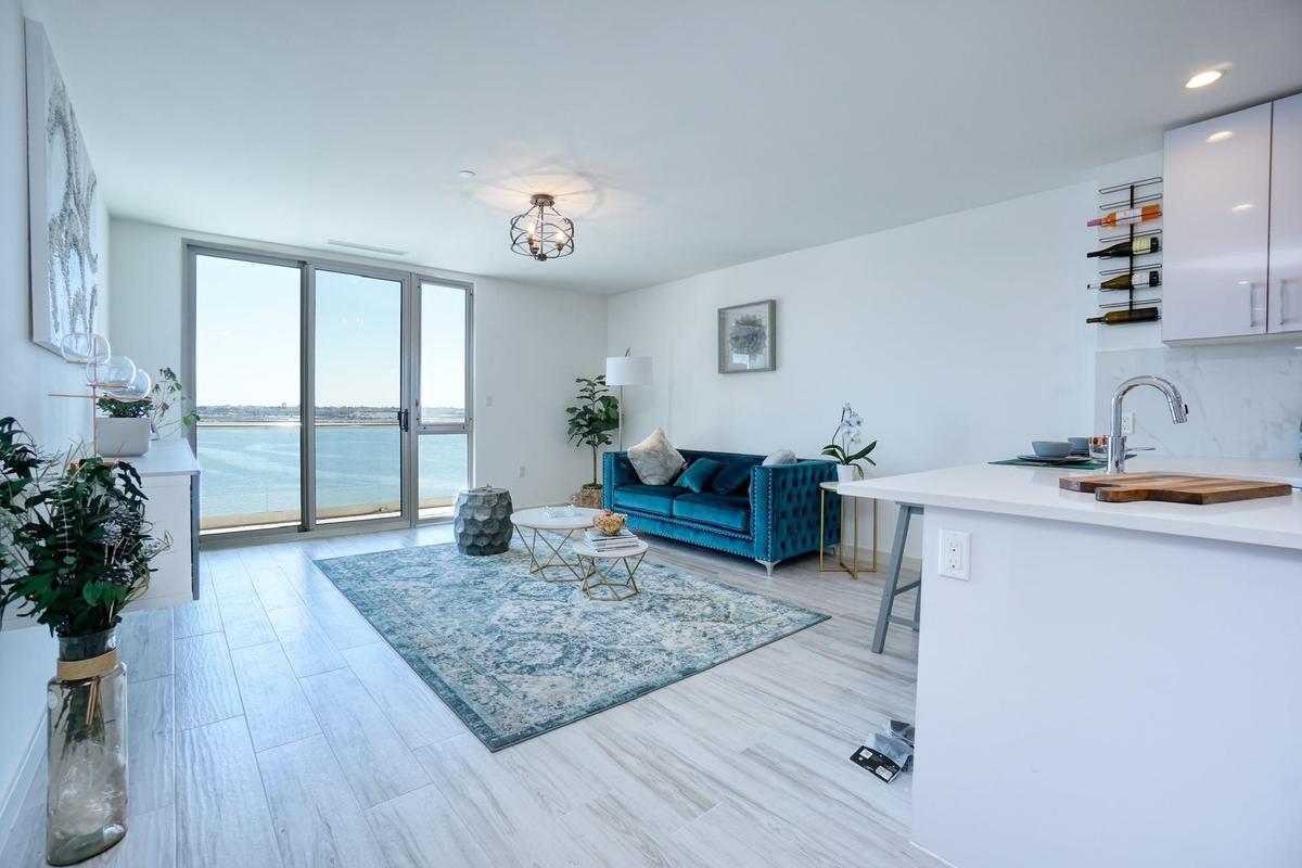 Living room featuring a water view, recessed lighting, light wood finished floors, and a notable chandelier