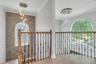 2nd story entry view, Stacked stone accent wall,Custom wood and decorative iron railing, glass chandelier, front pictureseque elliptical window adding
