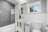 Bathroom featuring a white vanity with vessel sink, a shower-over-tub combination with glass partition.