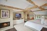 Bedroom featuring dark wood-style flooring and a fireplace with flush hearth