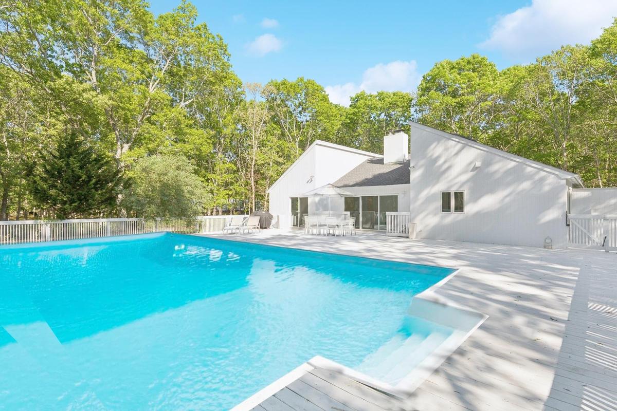 View of pool featuring outdoor dining space, a patio area, a gate, and view of scattered trees