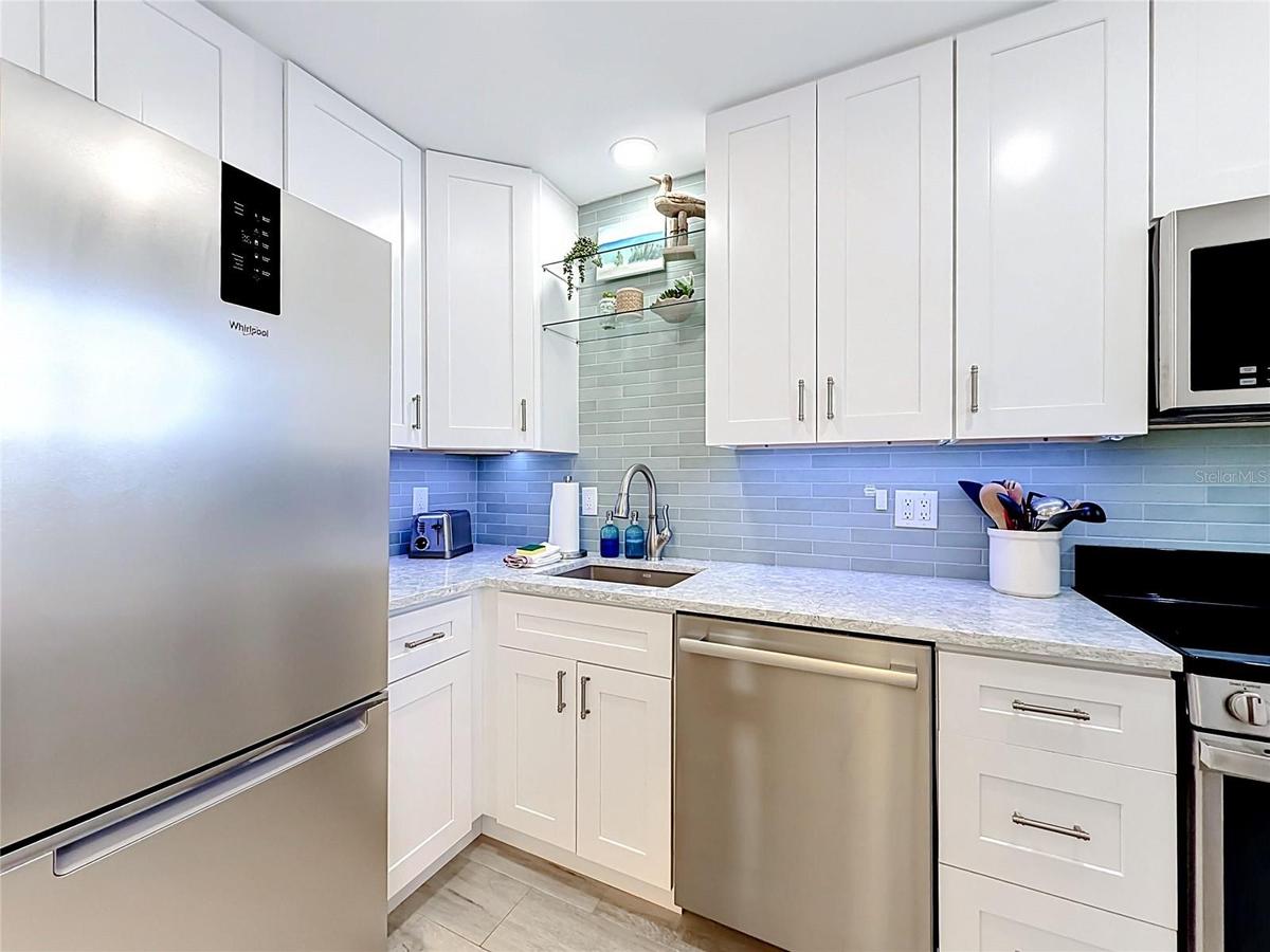 Your custom kitchen has under counter lighting, glass shelves and a beautiful backsplash along new cabinets and appliances.