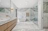 Full bathroom featuring stone wall, a freestanding bath, a marble finish shower, light marble finish flooring, and vanity