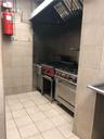 Kitchen with high end stove, tile walls, ventilation hood, and light tile patterned floors