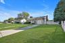 Ranch-style home with a chimney, concrete driveway, brick siding, an attached garage, and a gate