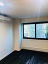 Empty room with baseboard heating, an AC wall unit, and dark wood-style floors