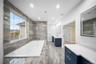 Bathroom with two vanities, a tub with jets, and recessed lighting