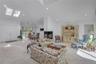 Vaulted ceiling living space featuring dual skylights, recessed lighting, a modern enclosed fireplace, and a dining area with a large window