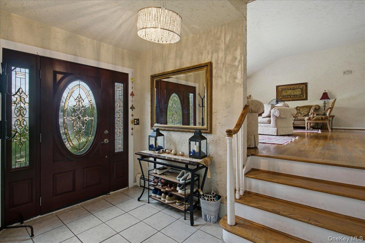 Entryway featuring a dark wood door with oval leaded glass, side panel windows, and a drum-style chandelier