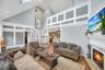Two-story living area featuring a vaulted ceiling with skylights, hardwood-finish flooring, a fireplace with a white mantel, and an open staircase wit
