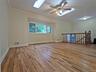 Spacious room featuring wood-finish flooring, a decorative ceiling fan, and two skylights for natural illumination
