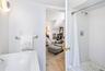 Primary bathroom featuring a white subway tile shower with hexagonal tile flooring, a white porcelain tub, and a chrome towel bar