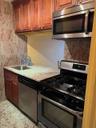 Kitchen with dishwasher, light stone countertops, range, and sink