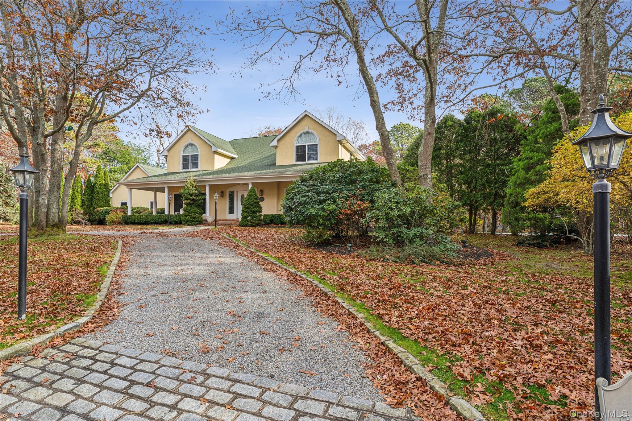View of front facade with stucco siding, a porch, and driveway