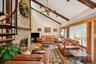 Living area featuring light wood-type flooring, beamed ceiling, high vaulted ceiling, a fireplace, and a ceiling fan