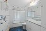 Bathroom featuring tile walls, shower / bath combination with glass door, vanity, and dark tile patterned floors