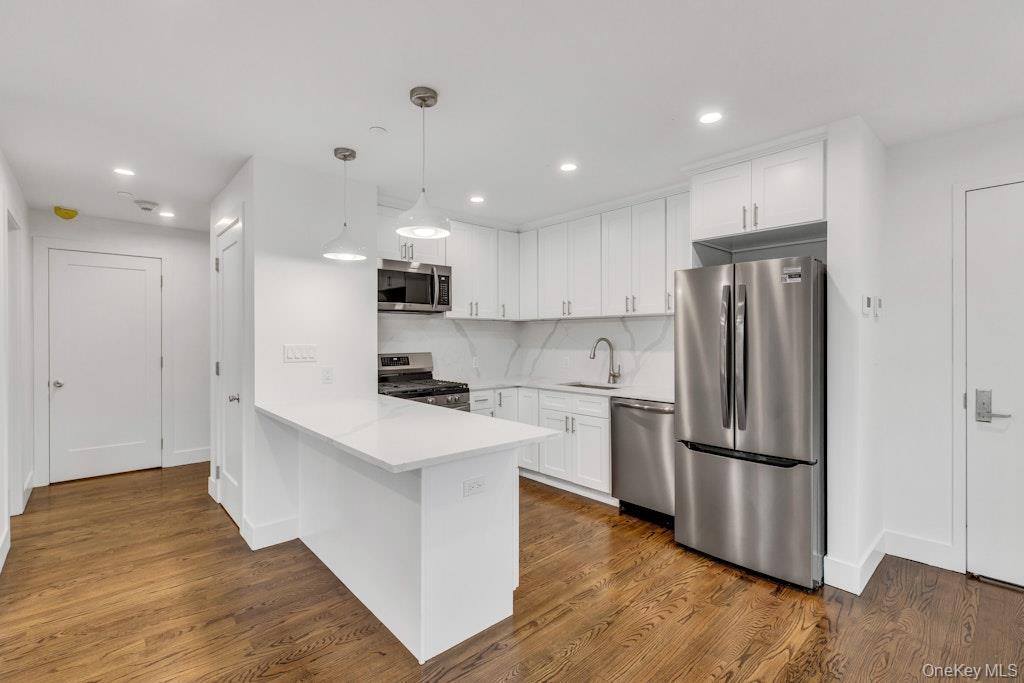 Kitchen with stainless steel appliances, white cabinetry, and a peninsula
