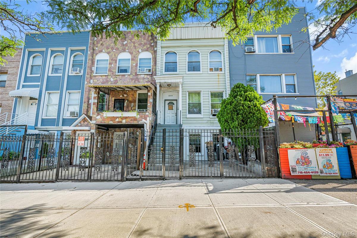 Multi-story residence featuring a stone-clad facade, wrought iron fencing, and an elevated entrance