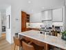Kitchen featuring wall chimney exhaust hood, open shelves, modern cabinets, a breakfast bar, and light stone counters