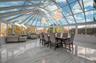 Sunroom / solarium featuring marble tiled flooring, high vaulted ceiling, a decorative wall, and a chandelier