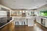Kitchen featuring pendant lighting, glass insert cabinets, white cabinets, appliances with stainless steel finishes, and dark wood-style flooring