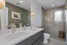 Bathroom featuring double vanity, a stall shower, recessed lighting, and wallpapered walls