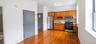 Kitchen area featuring wood-finish flooring, light wood cabinetry, and stainless steel appliances including a refrigerator, range, and microwave