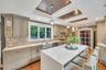 Expansive kitchen featuring a large central island with seating, a deep farmhouse-style sink, a patterned tile backsplash, and recessed and pendant li
