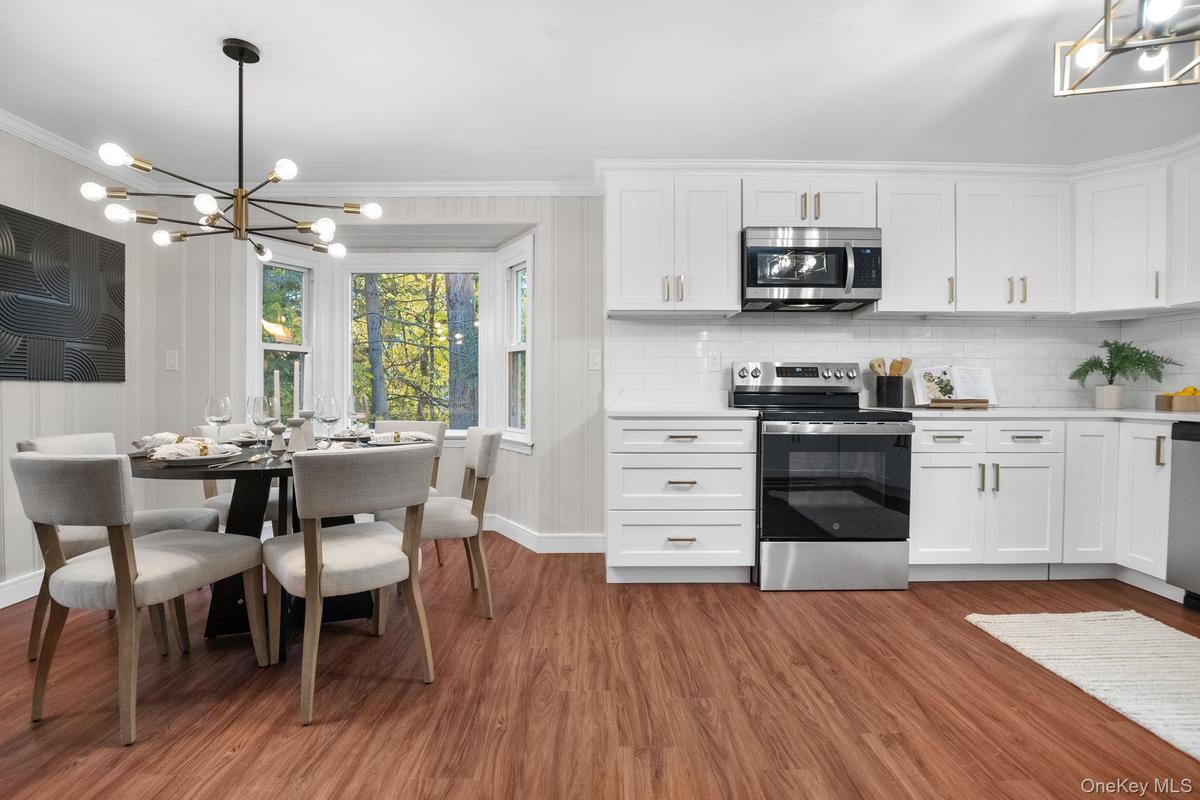 Newly renovated kitchen and dining area featuring quartz counters, stainless steel appliances, and a bay window that fills the space with natural ligh