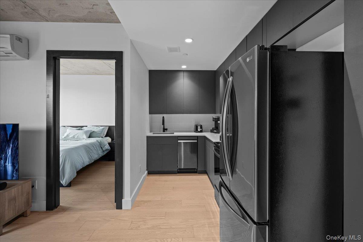 Kitchen featuring refrigerator with ice dispenser, modern cabinets, light wood-type flooring, recessed lighting, and stainless steel dishwasher