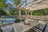 Fenced backyard with a covered pool, outdoor dining area, a pergola, and a patio