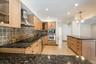 Kitchen featuring light wood-finish cabinetry, dark speckled countertops, and an integrated wall oven with a microwave