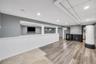 Spacious lower level featuring wood-finish flooring, recessed lighting, and a built-in wet bar with a beverage refrigerator