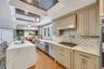 Kitchen featuring a waterfall island with a light-toned countertop, pendant lighting, recessed lighting, wood-finish flooring, and light-toned cabinet