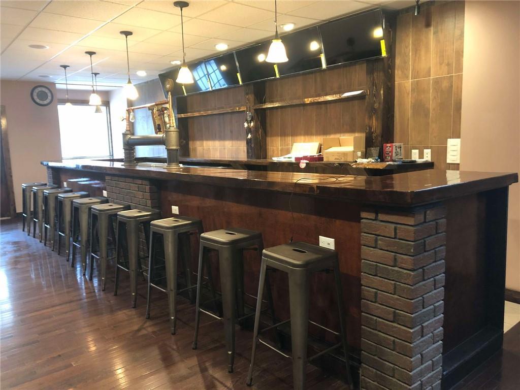Bar featuring wood walls, decorative light fixtures, and dark hardwood / wood-style floors