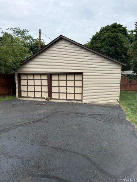 Detached two-car garage featuring light-toned siding, a dark gable roof, and two garage doors with grid detailing