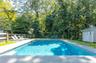 Swimming pool with a storage shed, a patio area, and view of wooded area