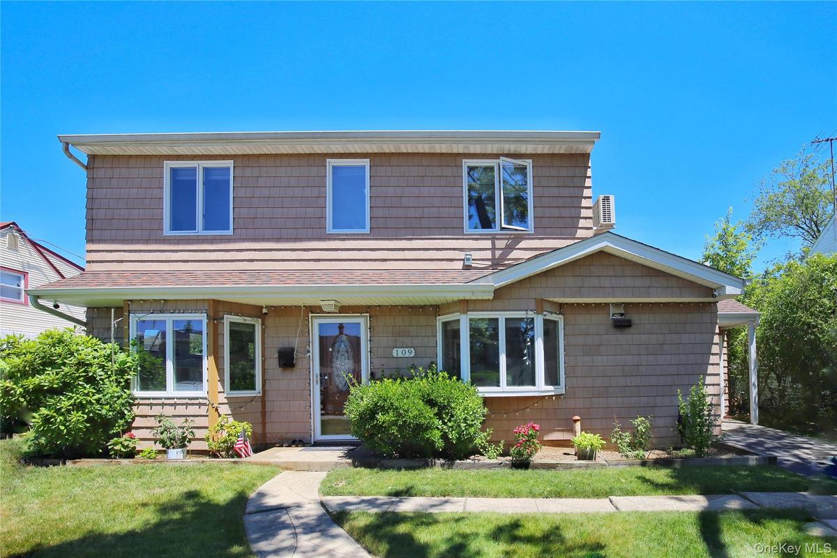 Two-story residence featuring tan shingle siding and a prominent bay window