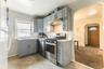 Kitchen with gray cabinetry, appliances with stainless steel finishes, arched walkways, and under cabinet range hood