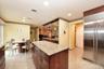 Kitchen featuring light stone countertops, a kitchen island, and stainless steel built in fridge
