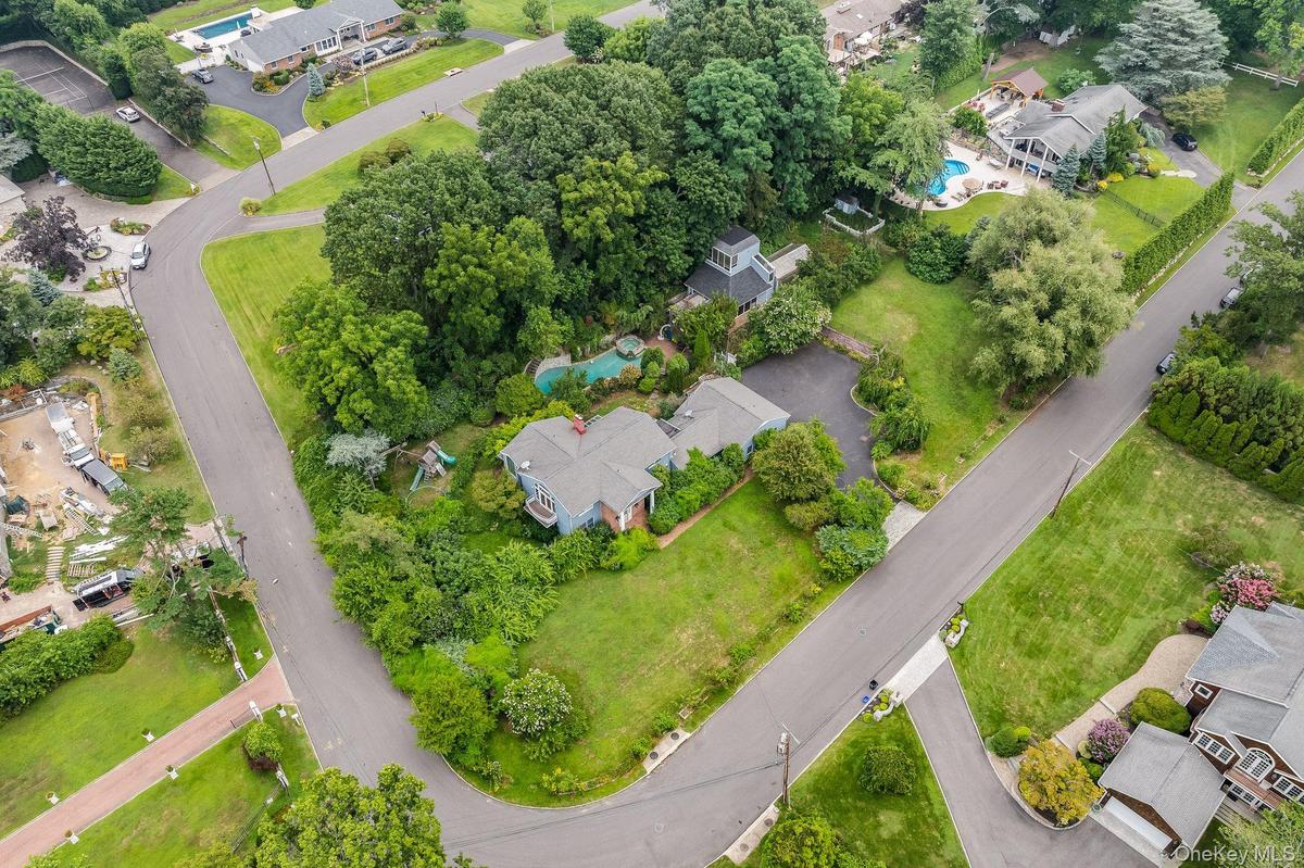 Aerial view of property and surrounding area featuring a pool area and nearby suburban area