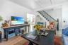 Living room with wood finished floors, stairs, and beamed ceiling