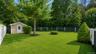 Expansive green lawn featuring a storage shed with siding, white trim, and a paneled door