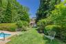Expansive backyard featuring a manicured lawn, established shrubbery, and mature trees