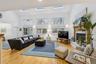 Living room with a glass covered fireplace, light wood-type flooring, high vaulted ceiling, and a skylight