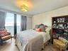 A spacious secondary bedroom with floor-to-ceiling glass and a peaceful view, effortless comfort for family and friends.